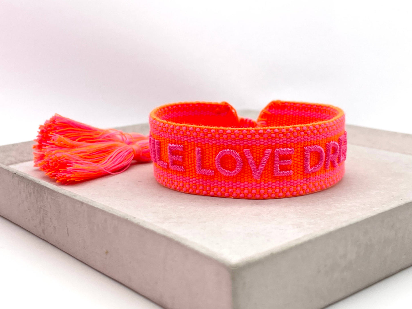 Hier ist die Produktbeschreibung für das "SMILE LOVE DREAM" Statement Armband mit einer passenden Überschrift: SMILE LOVE DREAM – Gewebtes Statement-Armband mit Stil